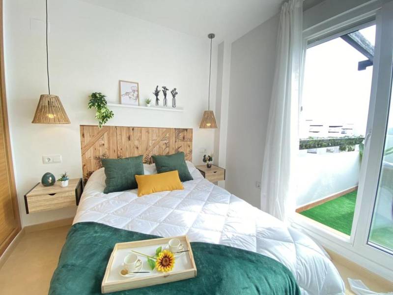 A bright bedroom with a bed, decorations, and access to the balcony in a 3-room apartment.