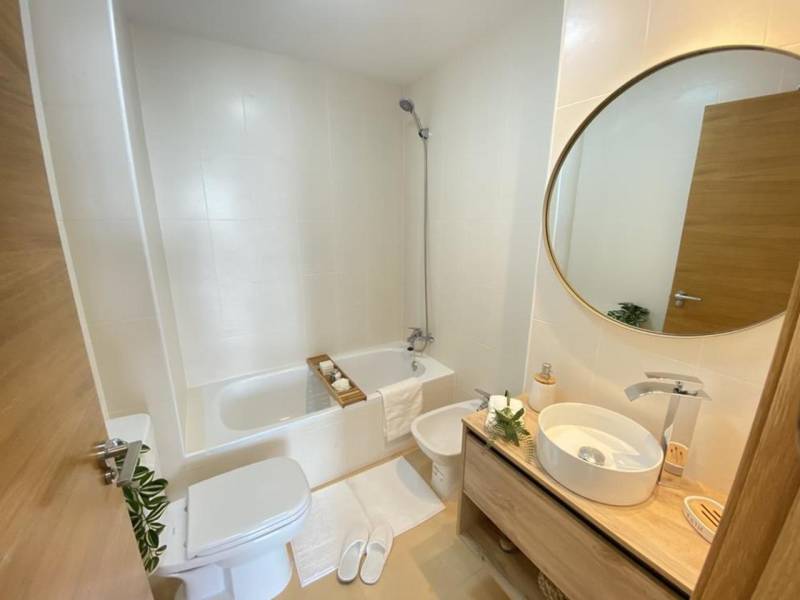 Bathroom in a 3-room apartment with a bathtub, toilet, and round mirror.