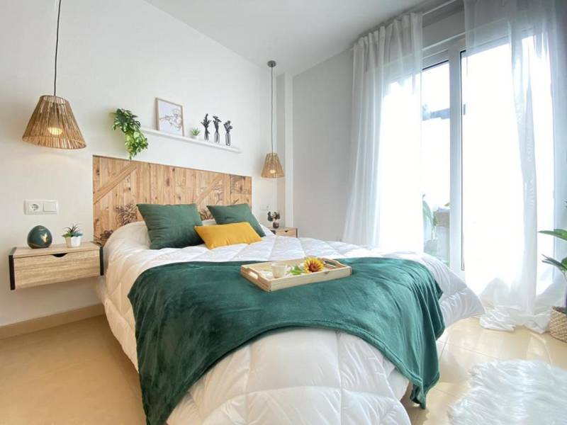 A bright bedroom in a 3-room apartment with a wooden headboard and green accessories.