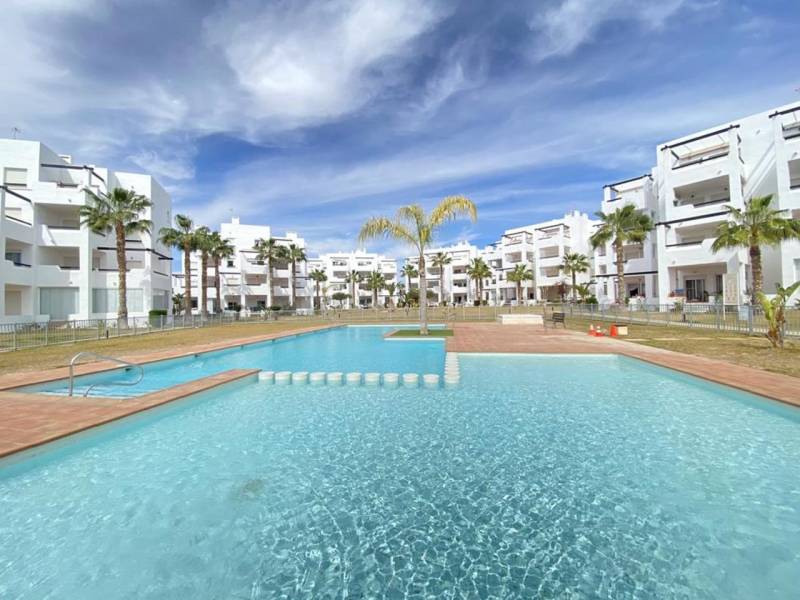 White residential buildings and a pool in the Las Terrasas de la Torre resort in Roldán.