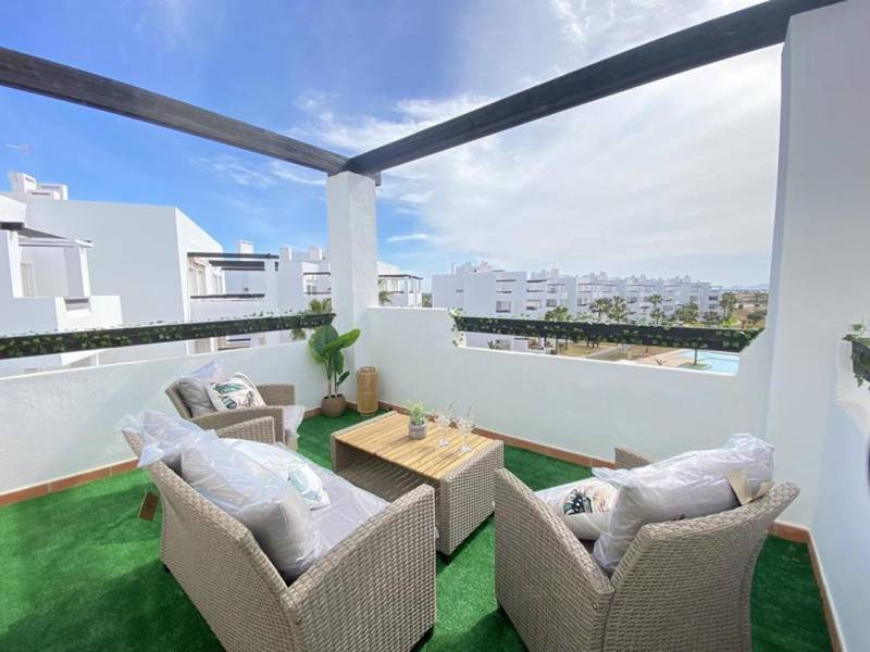 A terrace in a 3-room apartment with a view of the resort and comfortable seating.