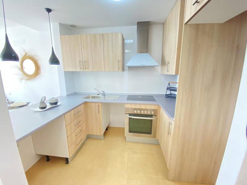 A kitchen in a 3-room apartment with wooden cabinets, a cooking area, and modern lights.