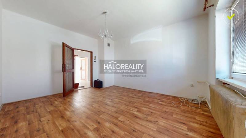A spacious room with wooden flooring, a chandelier, and open doors in a family house.