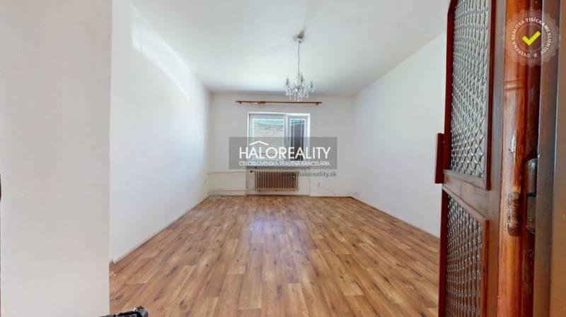 An empty room with a wooden floor and a chandelier, in a family house.