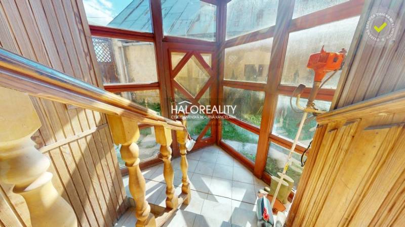 Wooden staircase with glass walls in a family house, equipped with garden tools.