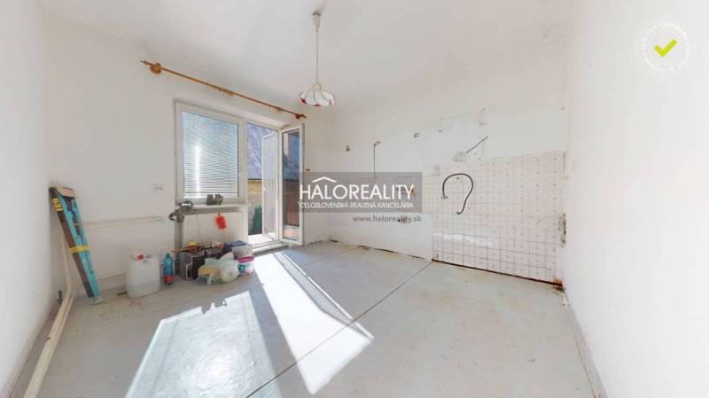 An empty room in a family house with a door to the terrace and preparation for a kitchen.