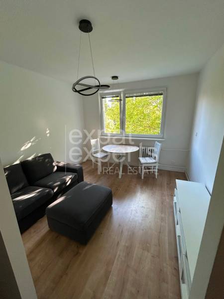 A bright living room with a sofa and a dining table in a two-room apartment.