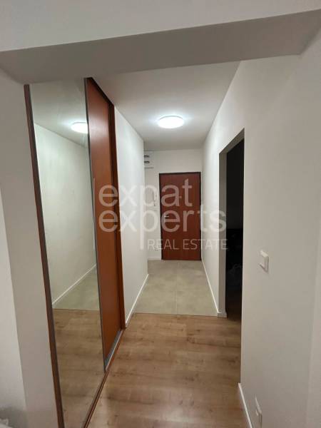 Hallway of a 2-room apartment with wooden flooring and a built-in wardrobe with a large mirror.