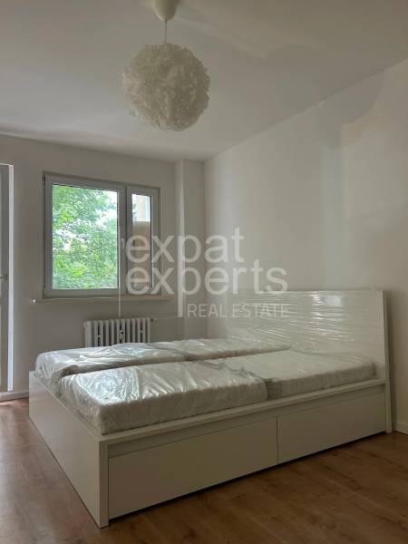 Bedroom in a 2-room apartment with large windows and a double bed.