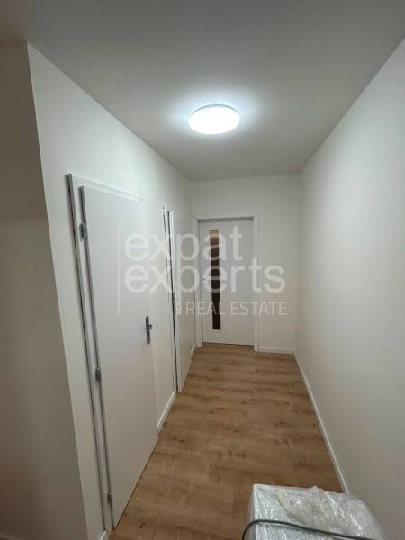 A hallway in a 2-room apartment with a wooden floor and white doors.