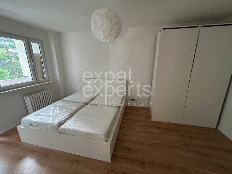 Bright bedroom with a built-in wardrobe and a double bed in a 2-room apartment.