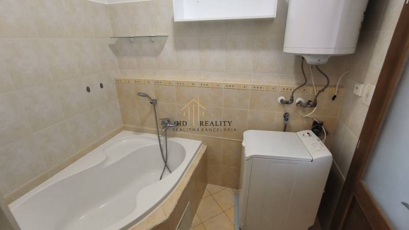 A bathroom in a 2-room apartment with a bathtub, boiler, and washing machine.