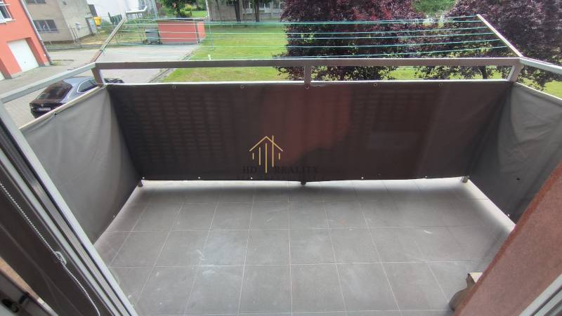 A balcony with a tiled floor and a view of greenery in a 2-room apartment in Liptovský Mikuláš.