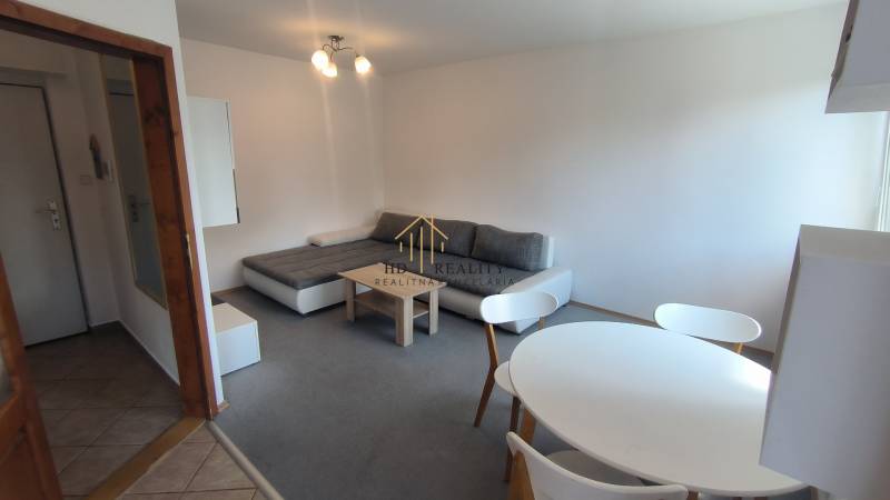Living room in a two-room apartment with a sofa, dining table, and entrance to the hallway.