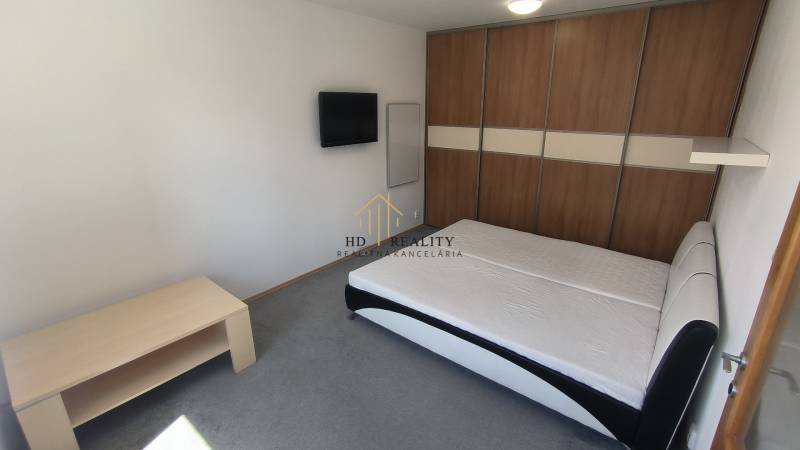 A bedroom with a double bed, a television, and a built-in wardrobe in a 2-room apartment.