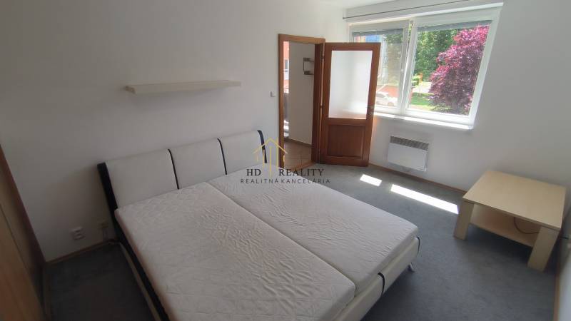 A bright room with a bed, a nightstand, and a window, suitable for a 2-room apartment.