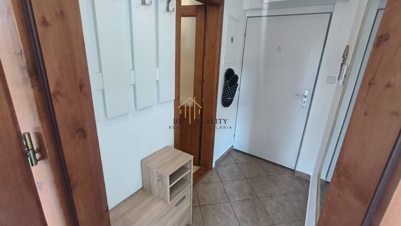 Entrance hall of a 2-room apartment with a built-in wardrobe, tiles, and doors with wood imitation.
