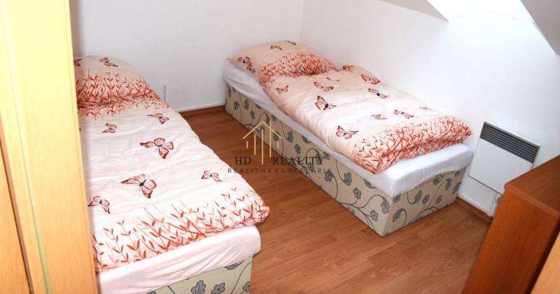 Children's room in a three-room apartment with two beds and simple wooden flooring.
