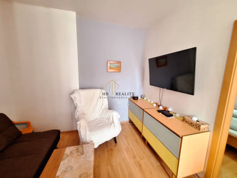Living room in a three-room apartment, with a TV on the wall and comfortable armchairs.