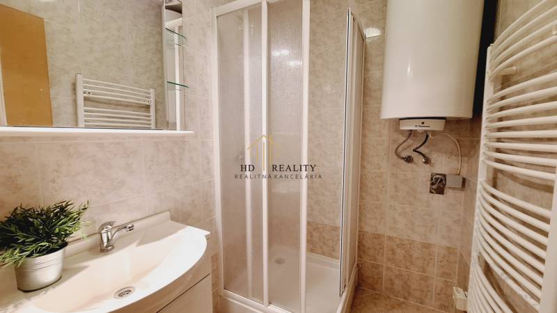 A bathroom in a 3-room apartment with a shower and a water heater.