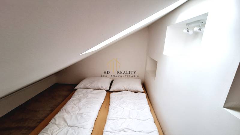 An attic bedroom with a single bed and a skylight in a 3-room apartment.