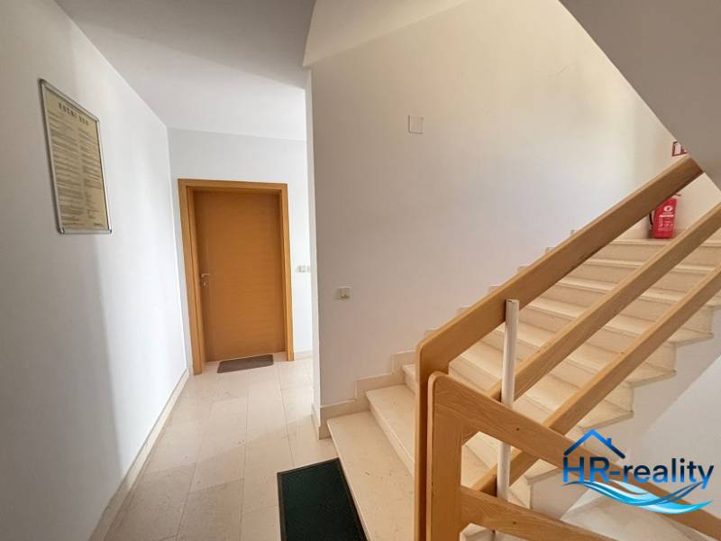 A hallway with a staircase and wooden railing in a 2-room apartment.