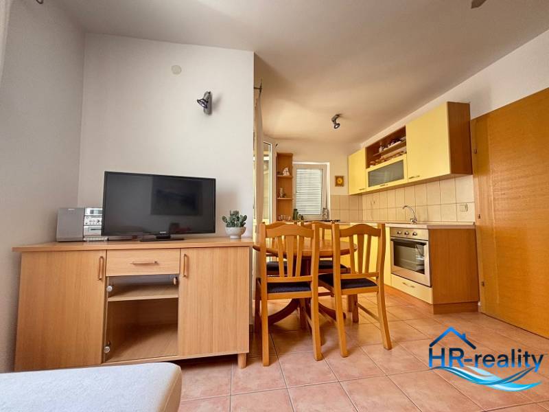 A kitchen with a dining area in a 2-room apartment, furnished with wooden furniture and appliances.