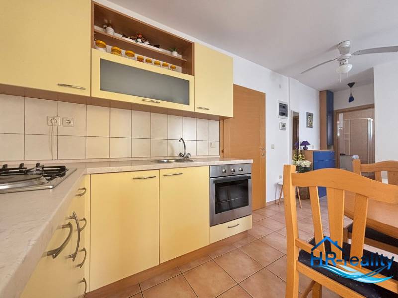 A kitchen in a 2-room apartment with wooden furniture and built-in appliances.