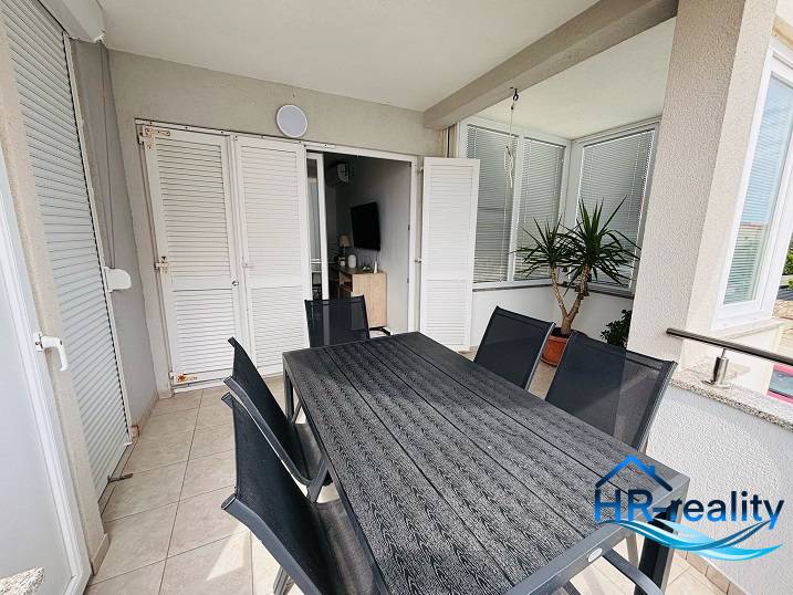 Terrace in a 3-room apartment with a view, table, chairs, and potted plants.