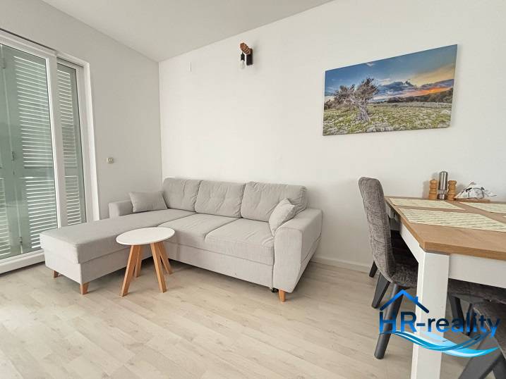 A bright living room in a three-room apartment, with a comfortable sofa and a dining table.