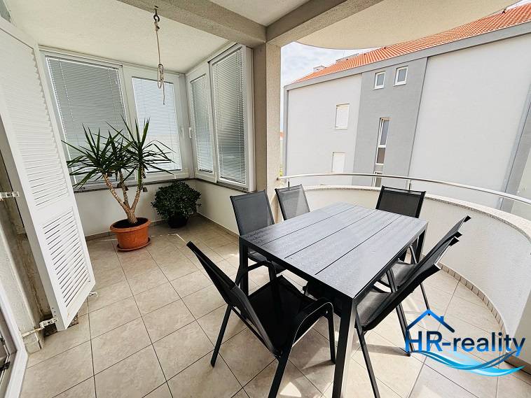 The balcony of a 3-room apartment in Novalja, with flowers and garden furniture on the tiles.