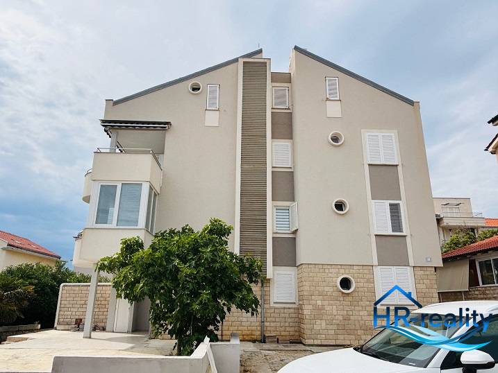 Exterior of a building in Novalja with a 3-room apartment, white shutters, and a balcony.