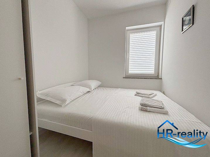A bright bedroom with a bed, window, and white bed linen in a three-room apartment.