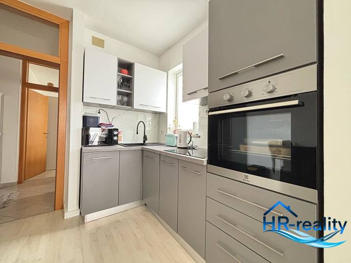 A kitchen in a 3-room apartment with a modern appliance and gray cabinets.