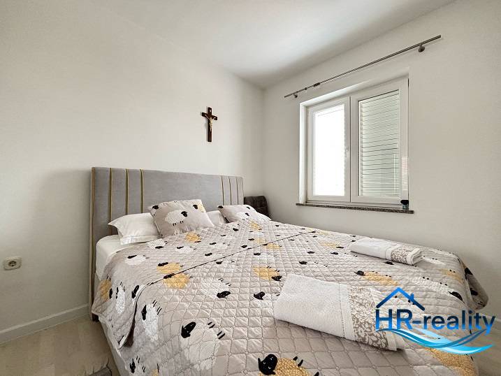 Bright bedroom with a comfortable bed in a 3-room apartment, cross on the wall.