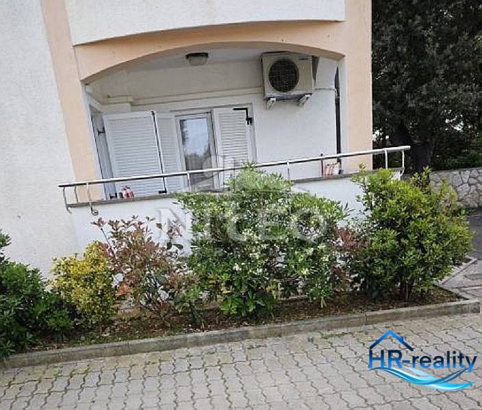 Facade of a 2-room apartment in Novalja with a balcony and greenery.