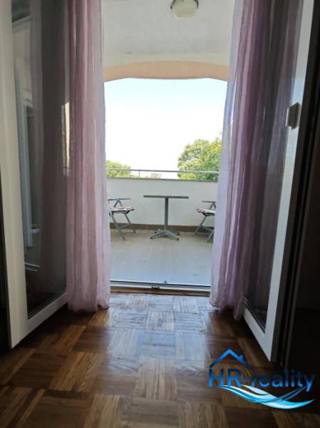 View from a 2-room apartment to a balcony with seating and a view of nature.