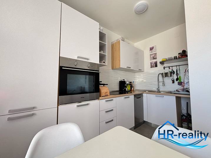 A kitchen in a 2-room apartment with modern white cabinets and built-in appliances.