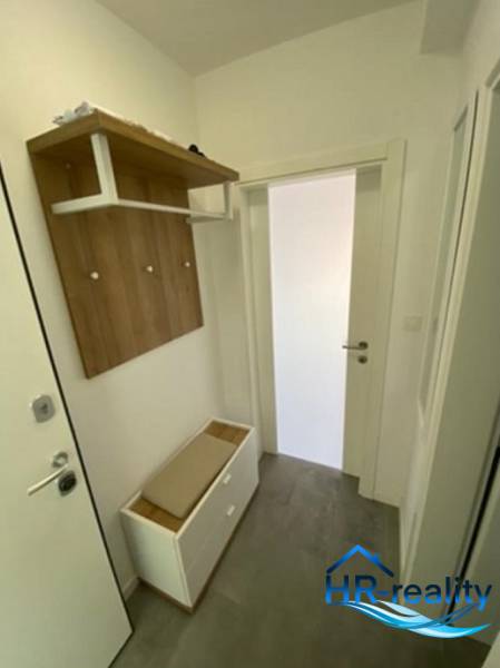 Hallway of a 2-room apartment with a coat rack, shoe cabinet, and white walls.