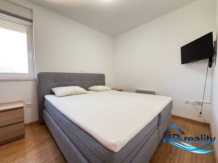 Bedroom with a double bed, television, and nightstands in a two-room apartment.