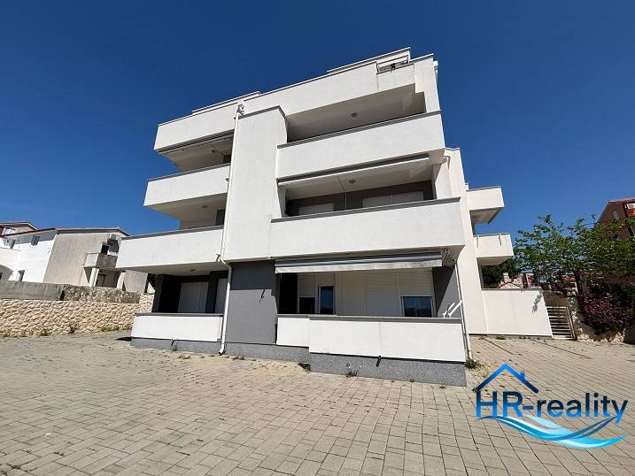 White building with terraces in Novalja, suitable for 2-bedroom apartments.