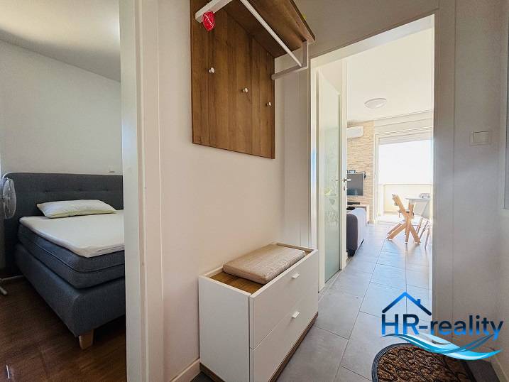 A corridor leading to the bedroom and living room in a 2-room apartment with light furniture.