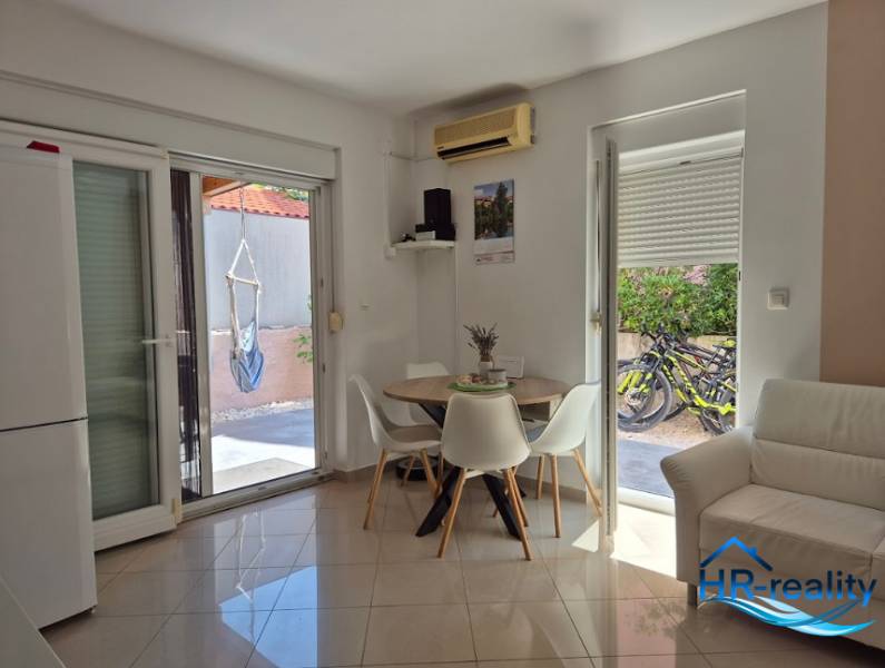 Interior of a 2-room apartment with a dining table, sofa, and access to the terrace.