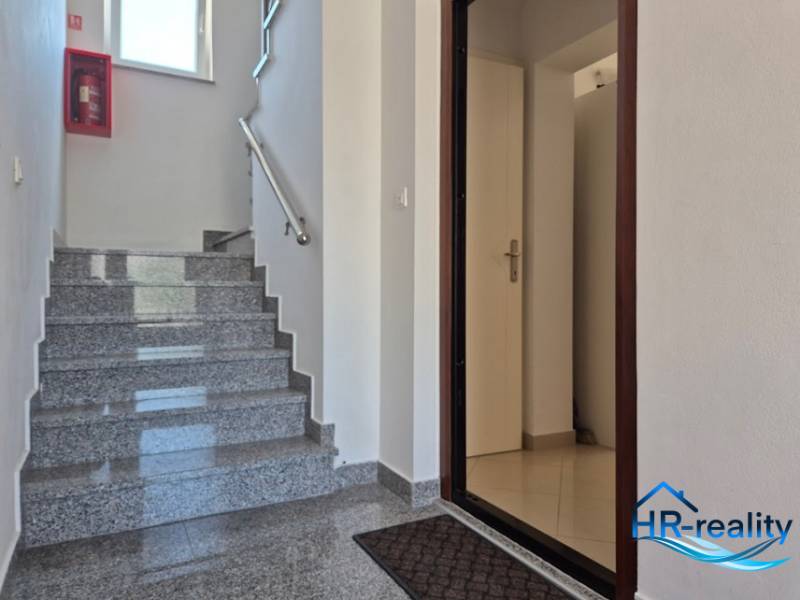 A clean staircase with open doors in a 2-room apartment with a marble floor.