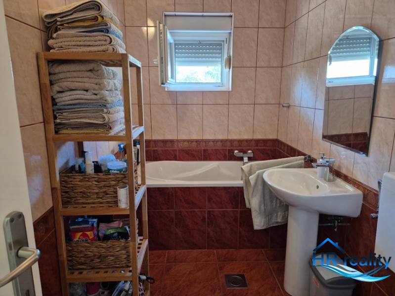 Bathroom in a 2-room apartment with a bathtub, shelves, and a window.