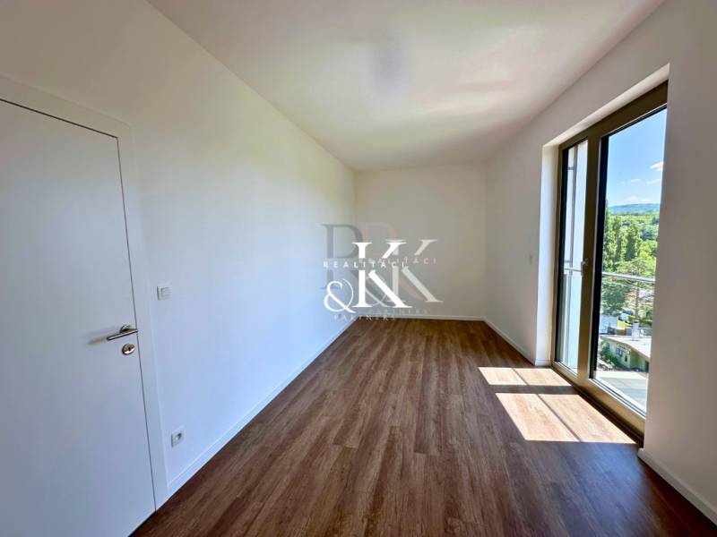 A room with a wooden floor and a large window in a 3-room apartment.