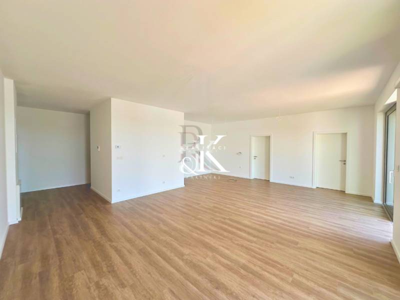 A spacious room with wooden flooring and white walls in a 3-room apartment.