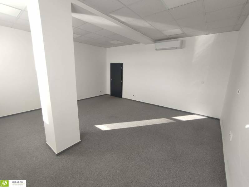 Office space with white walls, gray carpet, and an air conditioning unit.
