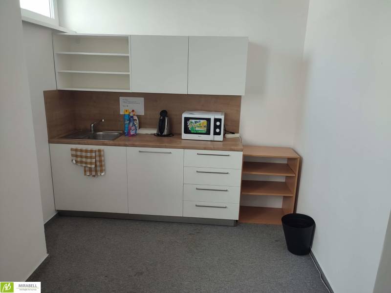 A kitchen counter in offices with a sink, microwave, and coffee maker.