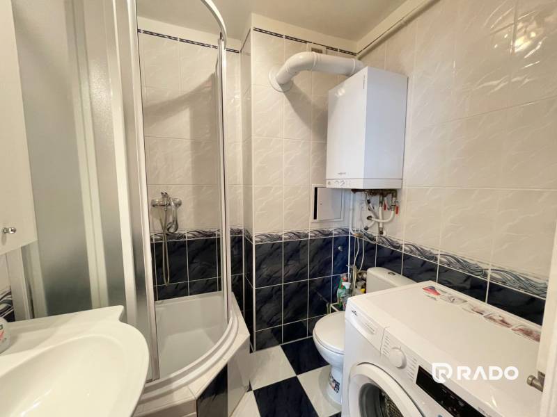 Bathroom in a 2-room apartment with a shower, washing machine, and gas boiler.